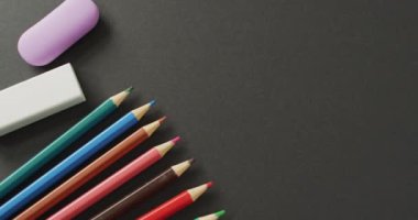 Video of composition with colorful crayons and school tools on grey surface with copy space. School equipment, tools, learning and education concept.