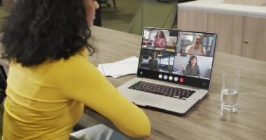 Biracial woman using laptop for video call, with diverse business colleagues on screen. Business communication technology and remote home working, digital composite video.
