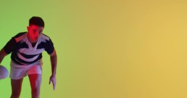 Beyaz erkek rugby oyuncusu sarı ışıkta ragbi topuyla zıplıyor. Spor, hareket, eğitim ve aktif yaşam tarzı kavramı.