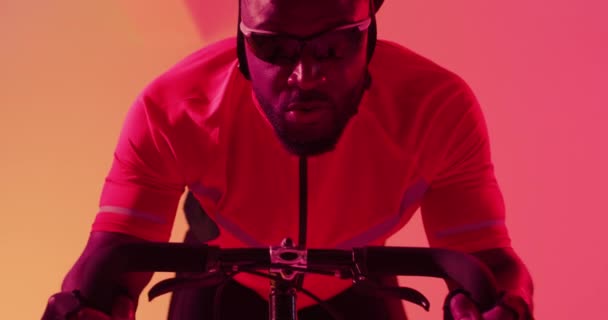 Odaklanmış Afrikalı Amerikalı Erkek Bisikletçinin Neon Turuncu Yıldırımla Sürüşünün Videosu — Stok video