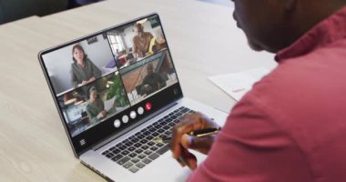 African american man using laptop for video call, with diverse business colleagues on screen. Business communication technology and remote home working, digital composite video.