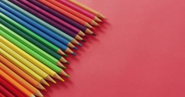 Kırmızı yüzeyinde renkli boya kalemleri olan kompozisyon videosu. Okul ekipmanları, araçlar, öğrenme ve yaratıcılık kavramı.