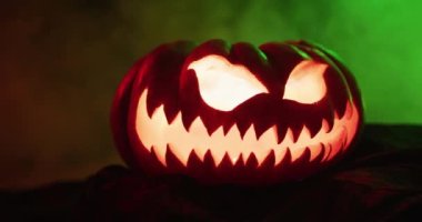 Video of halloween carved pumpkin with smoke and green light on black background. Halloween, autumn, tradition and celebration concept.