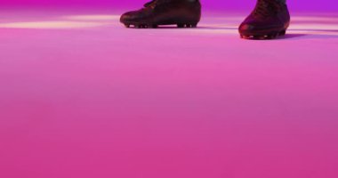 Male soccer player with football over neon pink lighting. Sport, movement, training and active lifestyle concept.
