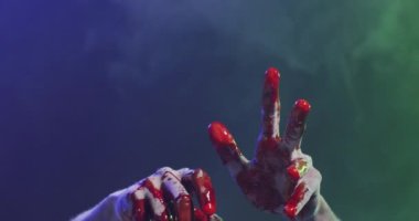 Video of hands covered with blood moving over smoke on black background. Halloween, autumn, tradition and celebration concept.