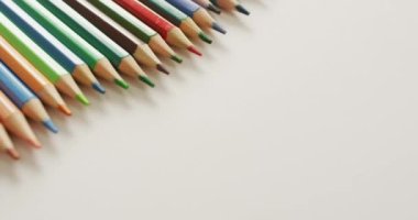 Video of composition with colorful crayons on white surface with copy space. School equipment, tools, learning and creativity concept.