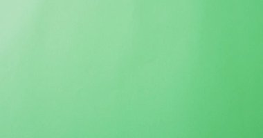 Video of composition with colorful crayons on green and yellow background with copy space. School equipment, tools, learning and education concept.