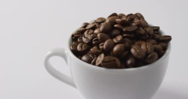 Video of cup of roasted brown coffee beans on white background. Coffee, refreshment and beverages.