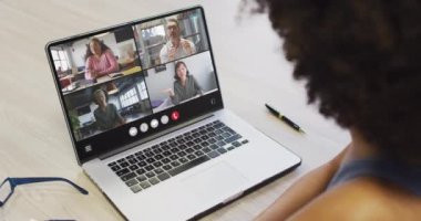 African american woman using laptop for video call, with diverse business colleagues on screen. Business communication technology and remote home working, digital composite video.