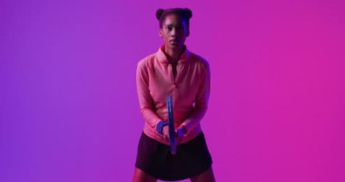 Neon pembeli raketli, odaklanmış Afrikalı Amerikalı bayan tenisçinin videosu. Spor, hareket, fitness ve aktif yaşam tarzı konsepti.