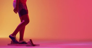 Odaklanmış Afrikalı Amerikalı kadın koşucunun neon turuncu yıldırıma hazırlandığı bir video. Spor, hareket, eğitim ve aktif yaşam tarzı kavramı.