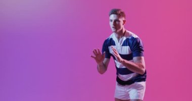 Beyaz erkek rugby oyuncusu pembe ışıkta rugby topu yakalıyor. Spor, hareket, eğitim ve aktif yaşam tarzı kavramı.