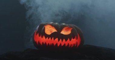 Video of halloween carved pumpkin with smoke on black background. Halloween, autumn, tradition and celebration concept.