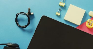 Video of composition of school items and tablet with copy space on blue and pink surface. School equipment, tools land earning with technology concept.