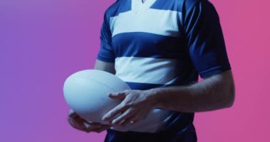 Pembe ışıkta rugby topu taşıyan beyaz erkek rugby oyuncusu. Spor, hareket, eğitim ve aktif yaşam tarzı kavramı.