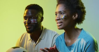 İngiliz ve Portekiz bayraklı neşeli Afro-Amerikan kadın ve erkek spor hayranlarının videosu. Spor, hayranlar, tezahürat ve duygu konsepti.