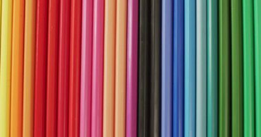 Video of colorful crayons lying in composition on wooden background. School equipment, tools, learning and education concept.