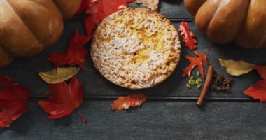 Video of autumn leaves, pumpkin, spices and pie on wooden background. Halloween, autumn, tradition and celebration concept.