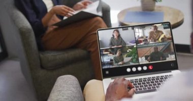 African american man using laptop for video call, with diverse business colleagues on screen. Business communication technology and remote home working, digital composite video.