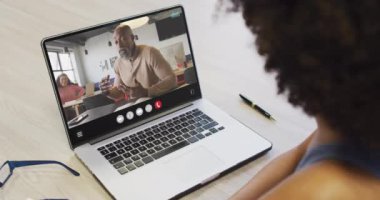 African american woman using laptop for video call, with business colleague on screen. Business communication technology and remote home working, digital composite video.
