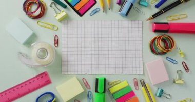 Video of checked sheet with copy space and school equipment on light green background. School equipment, tools, learning and education concept.