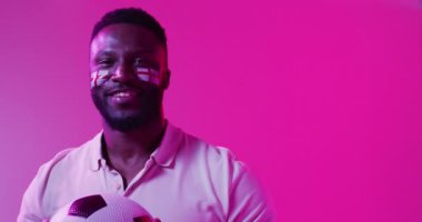 Neon pembe yıldırımlı İngiltere bayraklarıyla mutlu Afrika kökenli Amerikalı erkek spor hayranının videosu. Spor, hareket, eğitim ve aktif yaşam tarzı kavramı.