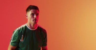 Kafkasyalı erkek futbolcu, kafasında neon pembe ışıkla futbolu geri getiriyor. Spor, hareket, eğitim ve aktif yaşam tarzı kavramı.