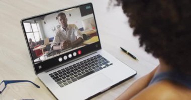 African american woman using laptop for video call, with business colleague on screen. Business communication technology and remote home working, digital composite video.