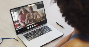African american woman using laptop for video call, with diverse business colleagues on screen. Business communication technology and remote home working, digital composite video.