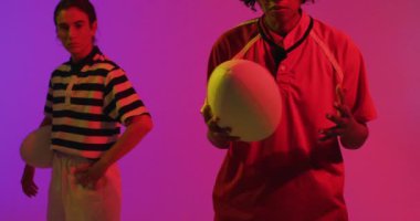 Neon pembe ışıkta rugby topu taşıyan çeşitli bayan rugby oyuncularının portresi. Spor, hareket, eğitim ve aktif yaşam tarzı kavramı.