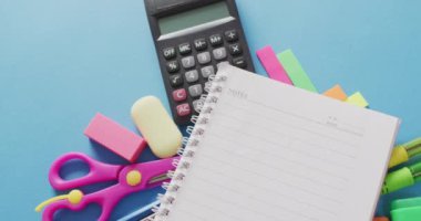 Video of school supplies, notebook, pens, marker pen over blue background. Education, learning and creativity.