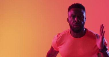 Neon turuncu yıldırımla koşan odaklanmış Afro-Amerikan erkek sporcunun videosu. Spor, hareket, eğitim ve aktif yaşam tarzı kavramı.