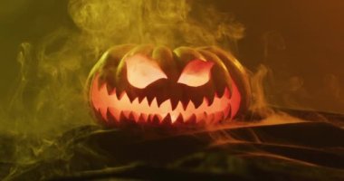 Video of halloween carved pumpkin with smoke and orange light on black background. Halloween, autumn, tradition and celebration concept.