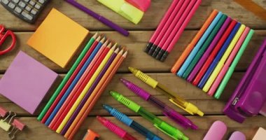 Video of composition with colorful school items on wooden background. School equipment, tools, learning and education concept.