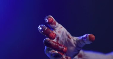 Video of hand covered with blood moving on black background. Halloween, autumn, tradition and celebration concept.