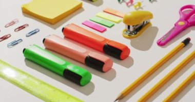 Video of markers, pencils, scissors and diverse office accessories lying on white surface. Business, working in office, equipment and tools concept.
