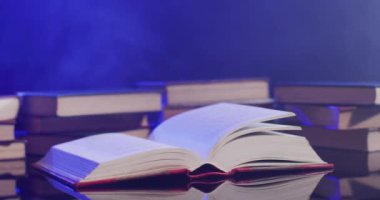 Video of pages in book moving over books and smoke on black background. Halloween, autumn, tradition and celebration concept.