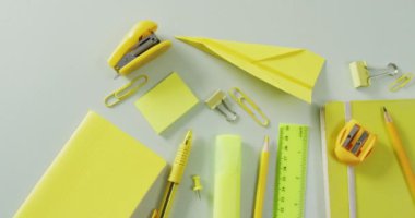 Video of composition of yellow school equipment on beige surface. School equipment, tools, learning and education concept.