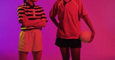 Neon pembe ışıkta rugby topu taşıyan çeşitli bayan rugby oyuncularının portresi. Spor, hareket, eğitim ve aktif yaşam tarzı kavramı.