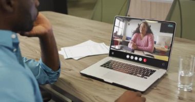 African american man using laptop for video call, with business colleague on screen. Business communication technology and remote home working, digital composite video.
