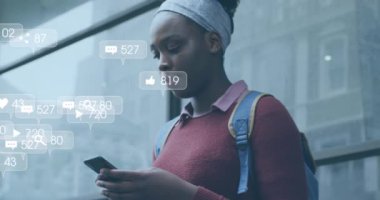 Akıllı telefon kullanan Afro-Amerikan kadınlarının üzerinde numaralar olan sosyal medya simgelerinin animasyonu. Sosyal medya ve dijital arayüz konsepti dijital olarak oluşturulmuş video.