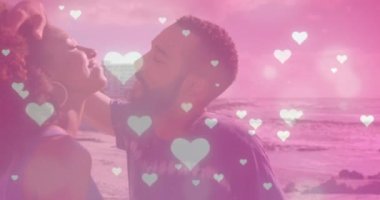 Sahilde öpüşen Afro-Amerikan çiftin üzerine düşen parlak pembe kalp simgelerinin canlandırması. Aşk ve ilişki kavramı