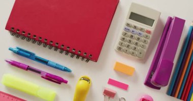 Video of composition of school items with notebook and calculator on white background. School equipment, tools, learning and education concept.
