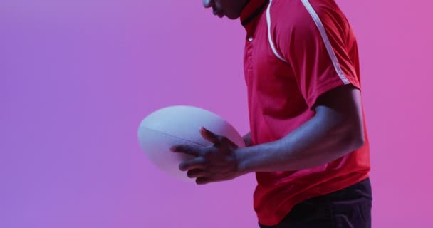 Afro Amerikaanse Mannelijke Rugbyspeler Met Rugbybal Roze Verlichting Sport Beweging — Stockvideo