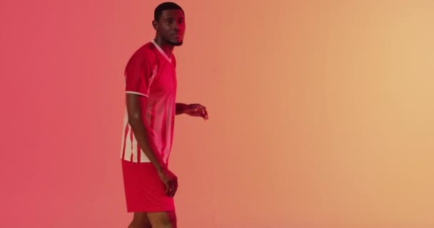 Afrykański Amerykański Piłkarz Powracający Piłki Nożnej Przy Neonowym Różowym Oświetleniu — Wideo stockowe