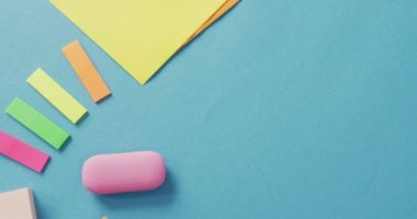 Video of post it, eraser and other school equipment on blue surface. School equipment, tools, learning and education concept.