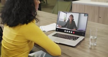 Biracial woman using laptop for video call, with business colleague on screen. Business communication technology and remote home working, digital composite video.