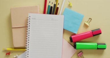 Video of notebook with copy space and school equipment on yellow background. School equipment, tools, learning and education concept.