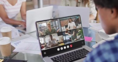 African american woman using laptop for video call, with diverse business colleagues on screen. Business communication technology and remote home working, digital composite video.