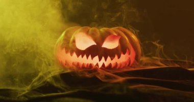 Video of halloween carved pumpkin with smoke and orange light on black background. Halloween, autumn, tradition and celebration concept.